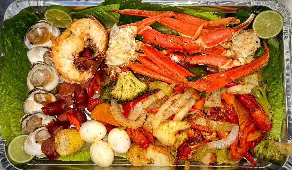Snow crab legs, shrimp, oysters and crawfish seafood boil platter at Golden Catch Fish Market Harlem